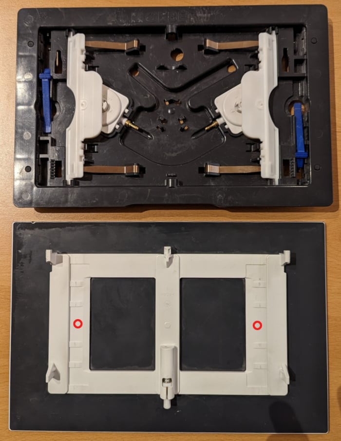 Plaque de déclenchement Geberit Sigma 70. En haut le mécanisme posé en applique et convertissant l'appui mécanique en une impulsion hydraulique. En bas, le dos de la plaque de déclenchement avec les deux emplacements où appliquer les patins.